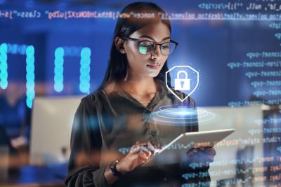 A women looks at a tablet and an image of a lock hovers above representing cybersecurity.
