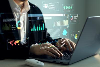 Person working on a laptop with data charts and reports overlayed on the screen, representing operational efficiency and business performance analysis.