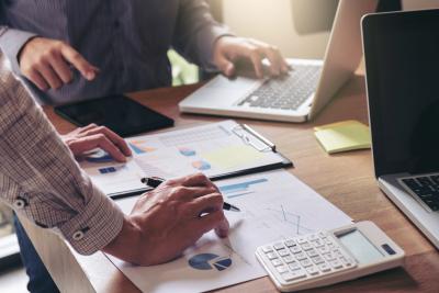 Arms stretch over a table as a team works on their strategy and business process.